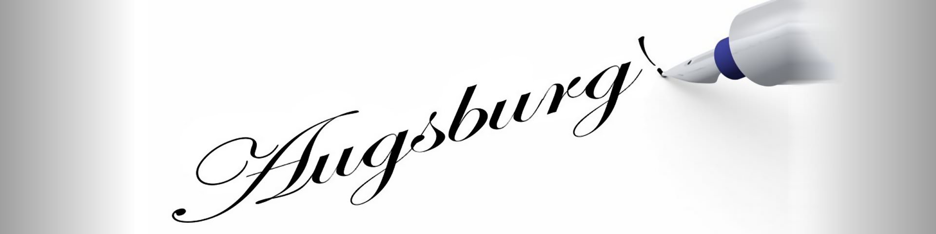 Ein Stift schreibt das Wort Augsburg auf ein Blatt.