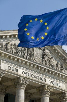 Reichstag in Berlin, Nahaufnahme mit Inschrift und die Europa-Flagge im Vordergrund.